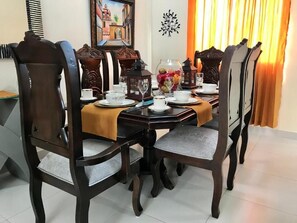 Guests can dine in style with a beautifully set table for four, featuring cushioned chairs and a decorative centerpiece.