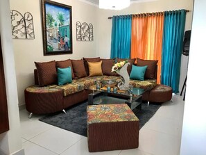 Relax in this stylish living room with a comfortable sectional sofa, a glass coffee table, and a beautiful painting on the wall.
