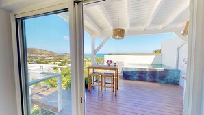A wooden deck with a table and chairs, overlooking a pool and a scenic view of the sea and hills. - SUNSEEKER SXM (Marigot)