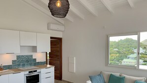 A modern kitchen with white cabinets, a built-in oven, and a wooden countertop. There is a window with a view of a green landscape. - SUNSEEKER SXM (Marigot)
