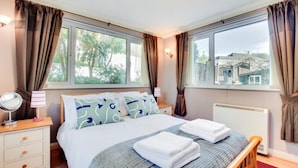 Une chambre à coucher avec un lit, des tables de chevet, une fenêtre et une vue sur l’extérieur.