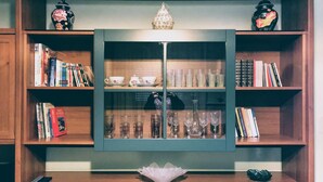 A room with a central cabinet containing glassware and books, flanked by shelves with books and decorative items.