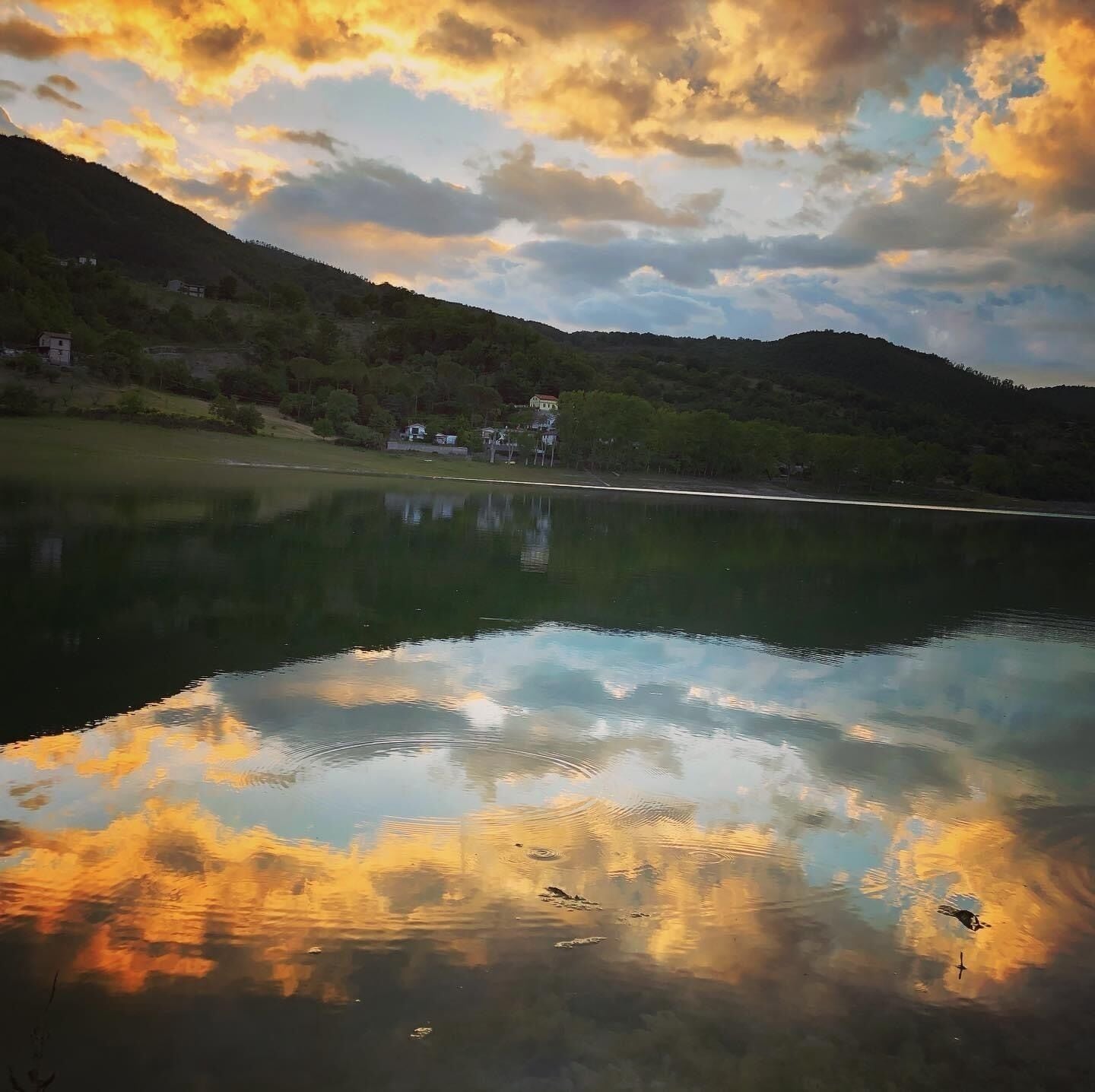 A calm lake reflecting the sky and surrounding landscape.