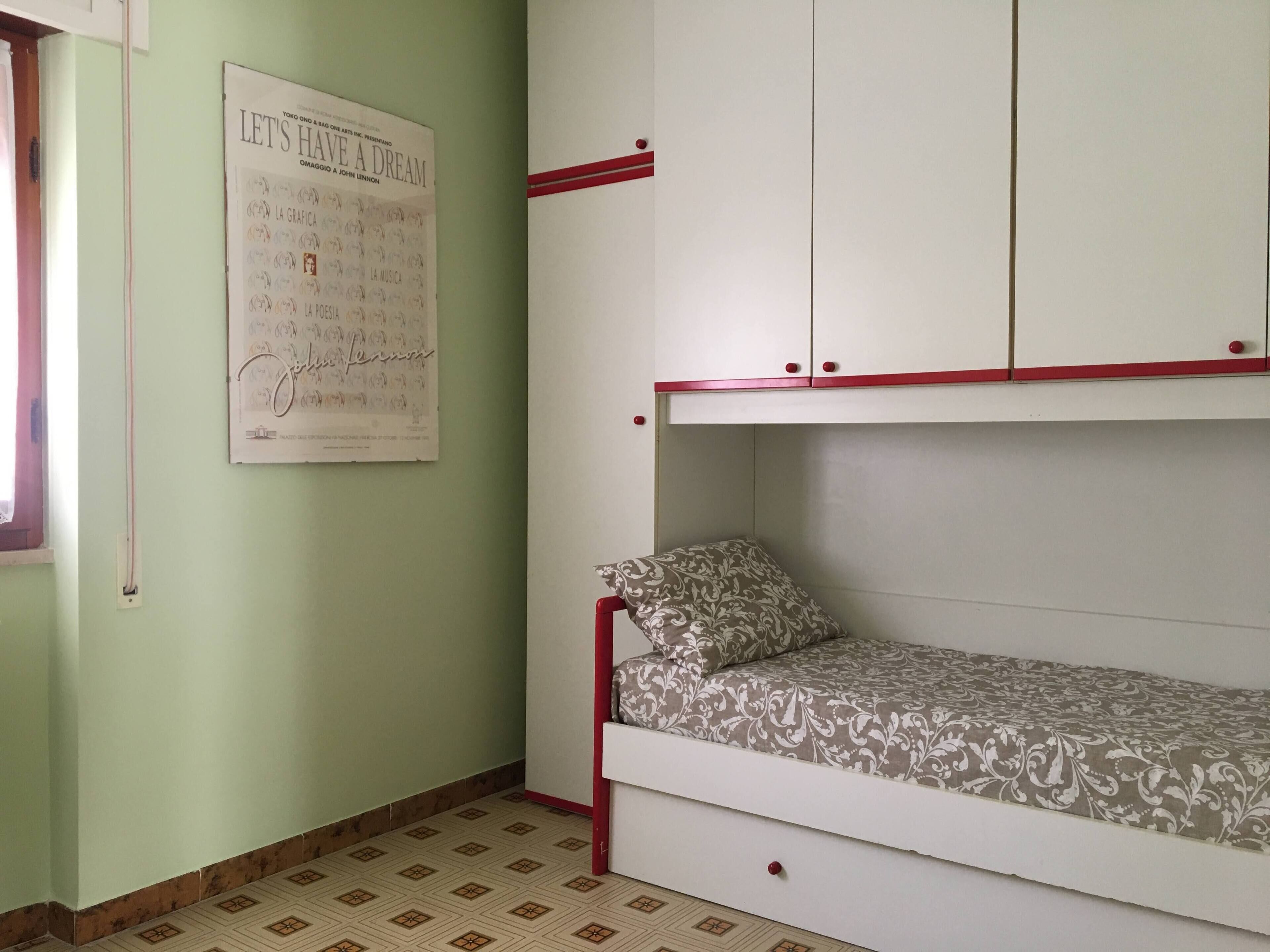 Ein Zimmer mit einem Stockbett, einem Poster an der Wand und einer gemusterten Bettdecke.