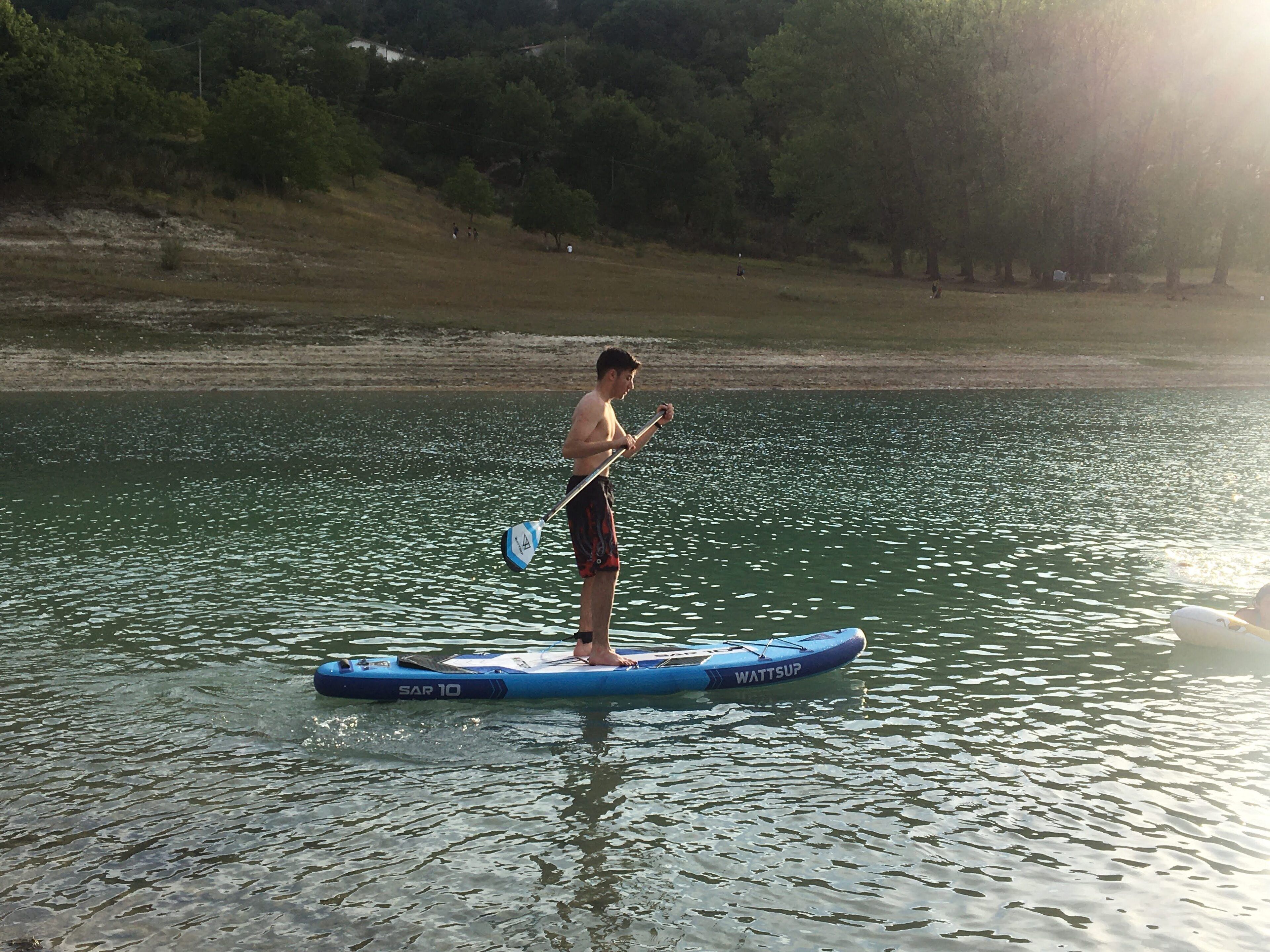 Iemand staat op een paddleboard in het water.