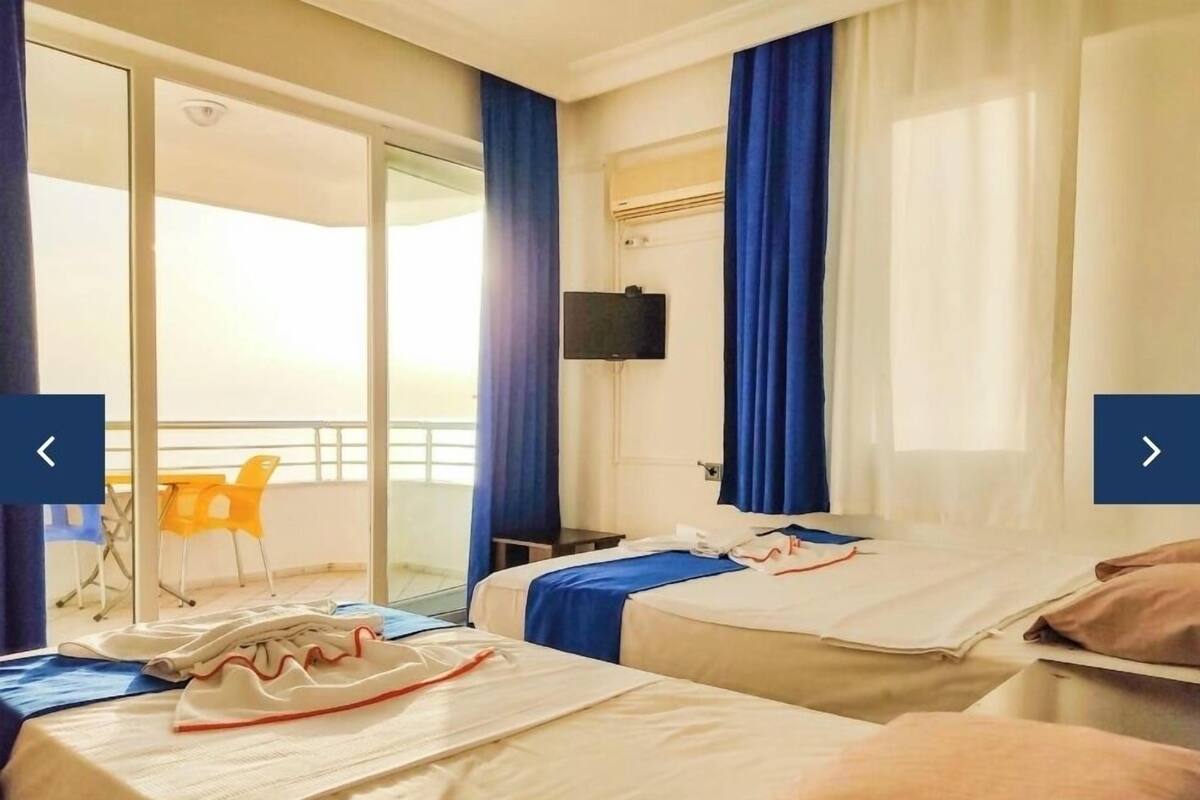 A hotel room with two beds, a TV, and a balcony with chairs.