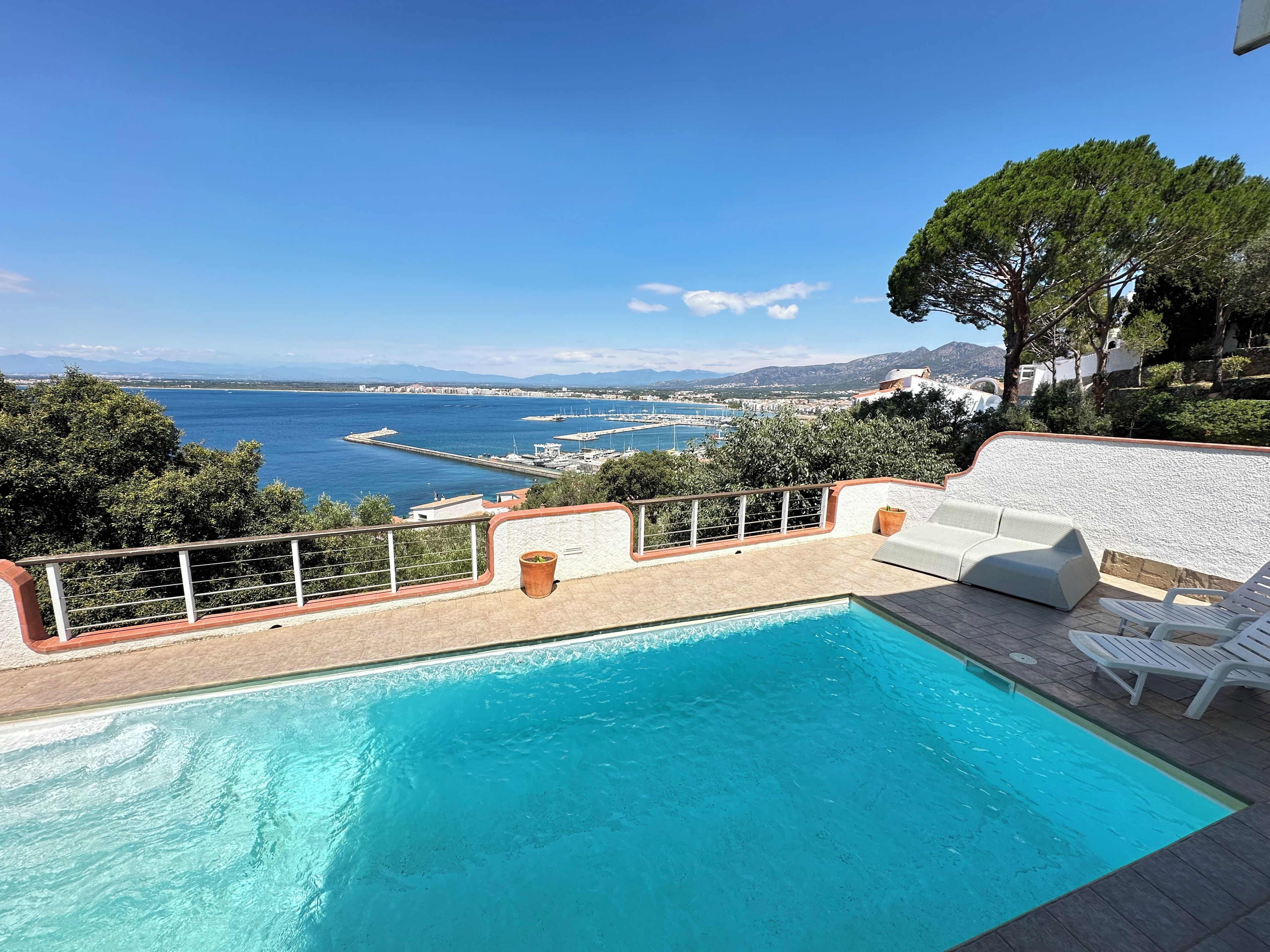 A pool area with a view of the sea and mountains.
