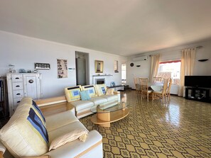 Een woonkamer met een bank, stoelen, een salontafel, een televisie en een vloer met een patroon.