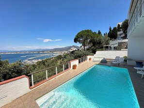 A swimming pool with a view of a marina and mountains in the distance.