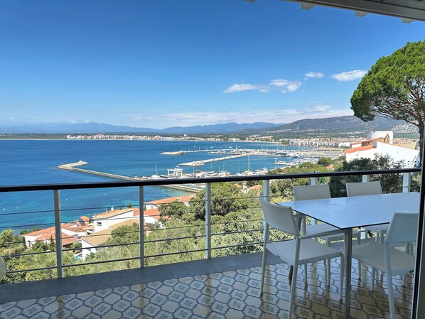 A balcony with a clear view of a marina and distant mountains.