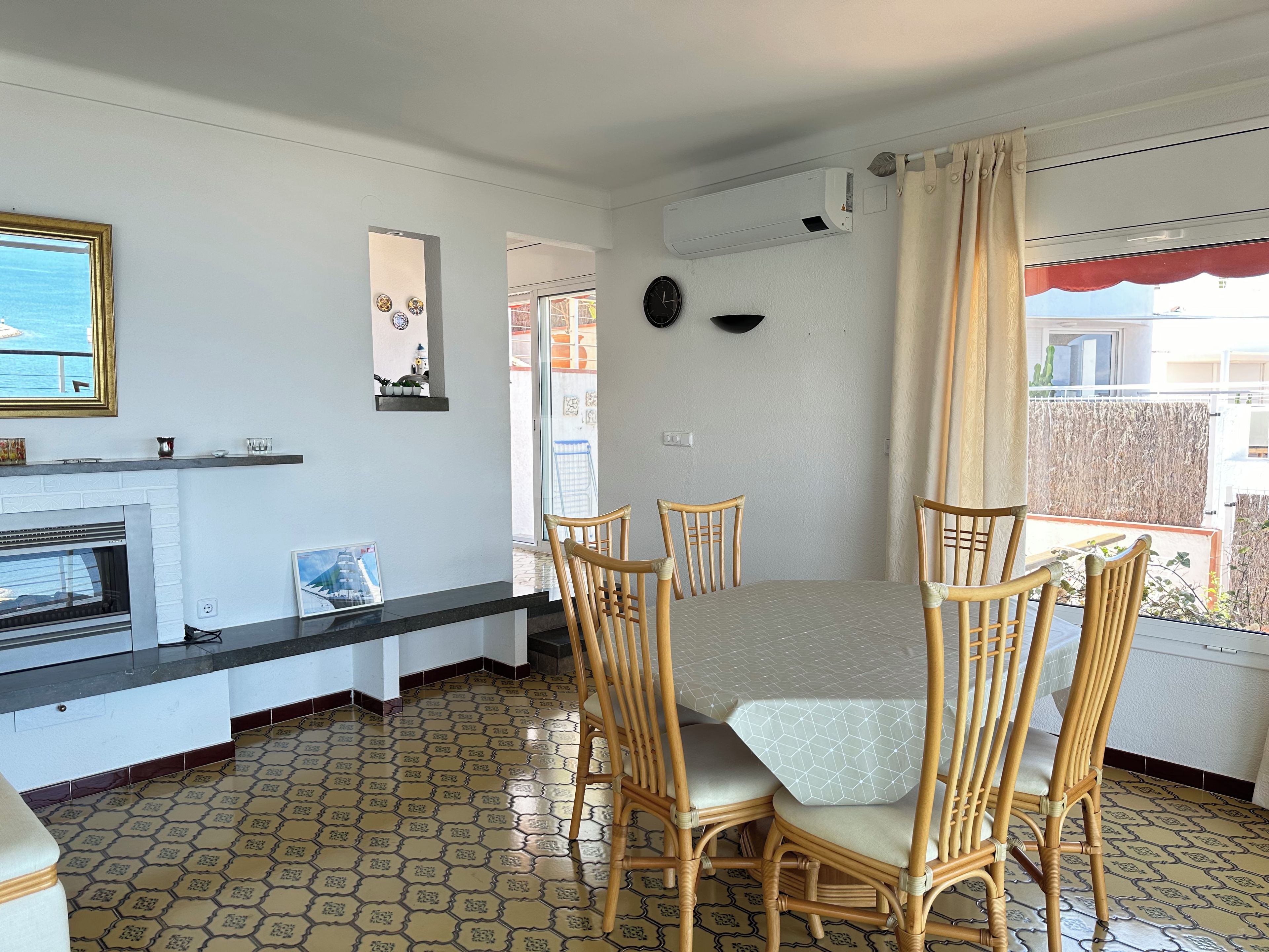 Un comedor con mesa y sillas, chimenea y vistas por una ventana.
