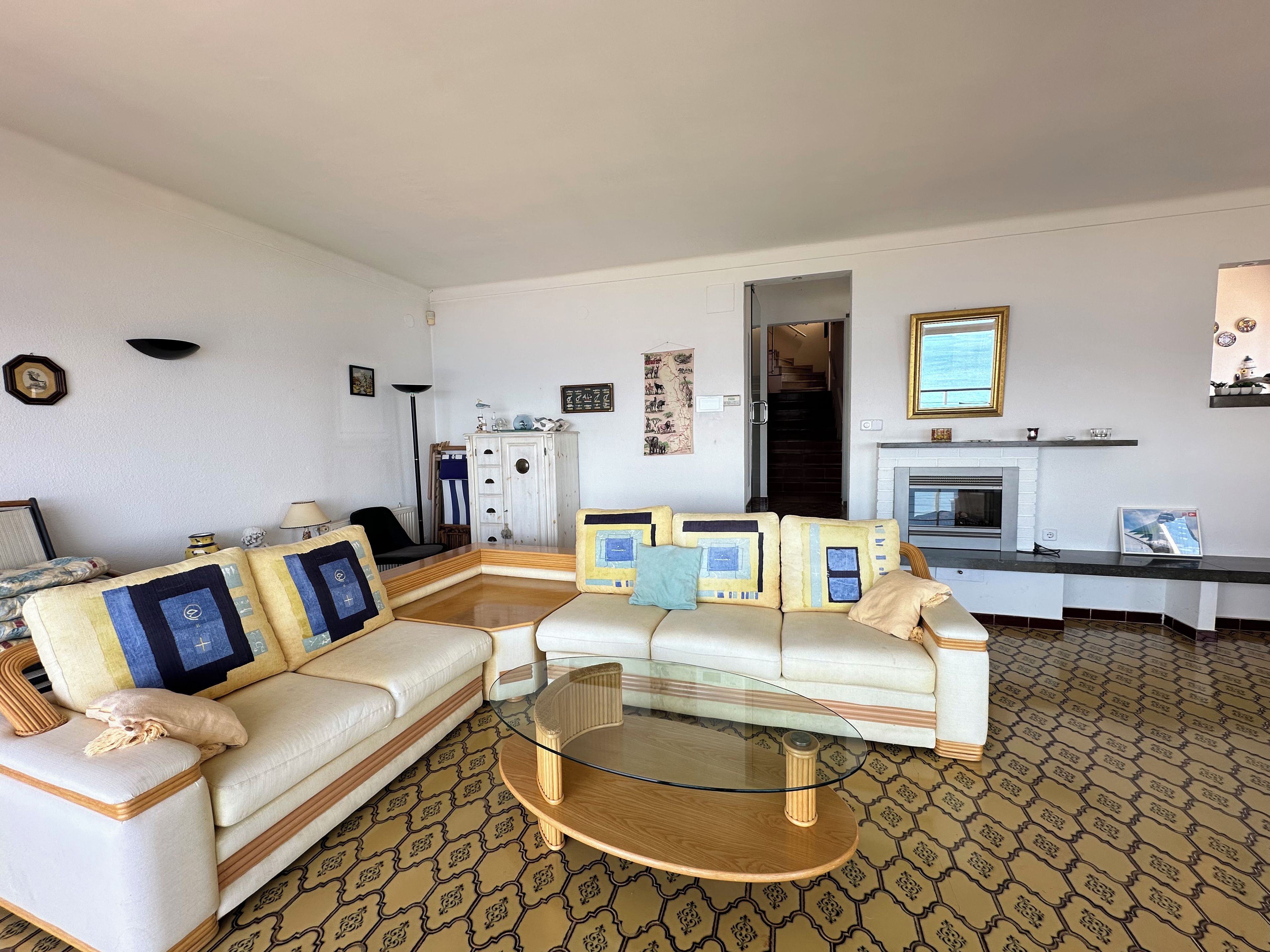 Ein Wohnzimmer mit einer Couch, einem Glastisch, einem gemusterten Teppich und einem Kamin.