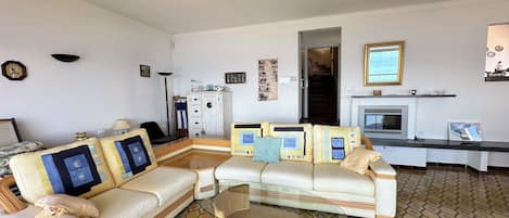 Ein Wohnzimmer mit einer Couch, einem Glastisch, einem gemusterten Teppich und einem Kamin.