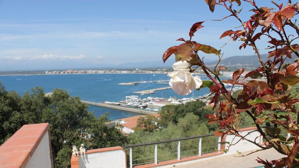 Un balcón con vistas a un puerto deportivo y al paisaje urbano costero.