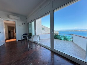 A room with a large sliding glass door leading to a balcony with a view of the sea.