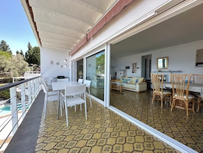 Een balkon met een tafel en stoelen, een bank, en een eettafel met stoelen in een kamer met een patroon vloer.