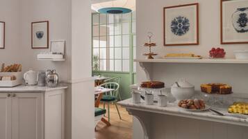 Una cocina con armarios blancos, encimera de mármol y diversos alimentos exhibidos en estanterías.