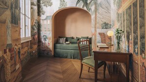 Une pièce avec une fresque murale, un lit, une chaise et une table.