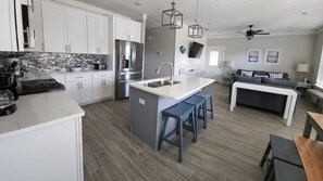 Una cocina moderna con armarios blancos, un refrigerador de acero inoxidable y una isla integrada con taburetes de bar.