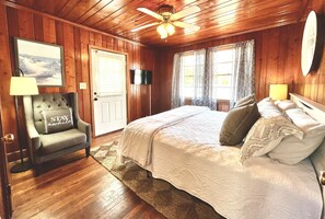 Relax in a classic bedroom with a large bed, tufted armchair, and flat-screen TV.