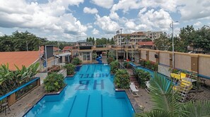 A hotel with a swimming pool, outdoor seating, and a view of the surrounding buildings. - Hoima Buffalo Hotel (Hoima)
