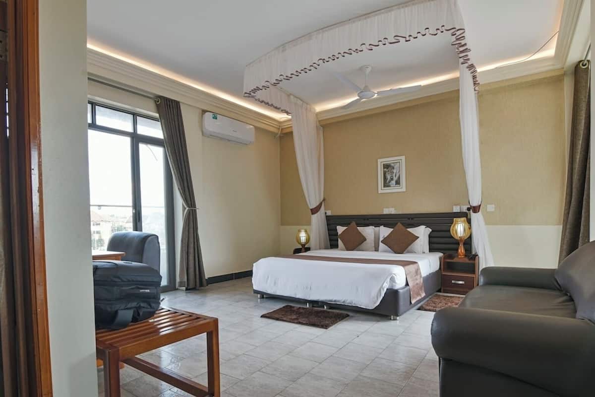 A hotel room with a bed, a sofa, a desk, and a chair.