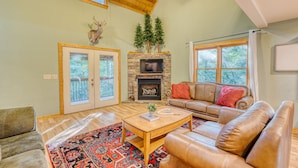 A spacious living room with a stone fireplace, leather sofas, and a large window.