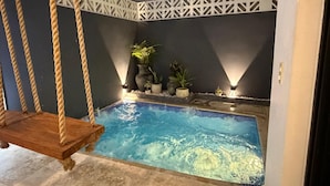 A small indoor pool with a swing chair, potted plants, and a decorative wall. - Modern Gated Townhome. 3BR for 6 guests. Walk to Restaurants. Private Jacuzzi (Tulum)