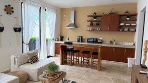 A modern kitchen with a central island, wooden bar stools, and a dining table. - Modern Gated Townhome. 3BR for 6 guests. Walk to Restaurants. Private Jacuzzi (Tulum)
