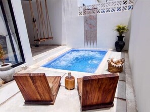 Relax in a serene outdoor oasis with a hot tub and comfortable seating area.