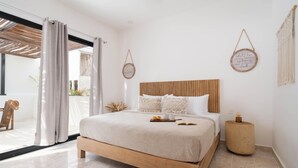 A bedroom with a wooden bed, a round bedside table, and a view of the outdoors. - Modern Gated Townhome. 3BR for 6 guests. Walk to Restaurants. Private Jacuzzi (Tulum)
