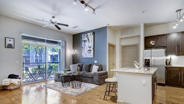 A modern kitchen with a central island, a dining area with a sofa and chairs, and a balcony with a view. - Stylish 2 BR in the Med Center near NRG Stadium (Houston)