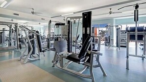 A gym with various exercise machines, mirrors, and ceiling fans. - Stylish 2 BR in the Med Center near NRG Stadium (Houston)