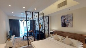 Een moderne hotelkamer met een groot bed, een bureau, een stoel, een bank en een decoratief scherm.