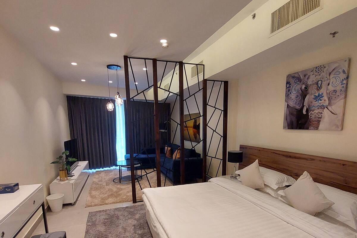 Une chambre d’hôtel moderne, dotée d’un grand lit, d’un bureau, d’une chaise et offrant une vue sur la ville.