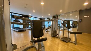 Een sportschool met trainingsapparatuur, houten vloeren en grote ramen.