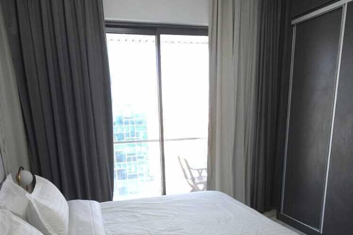 Une chambre à coucher avec un lit, des rideaux, une fenêtre et une vue sur des immeubles.
