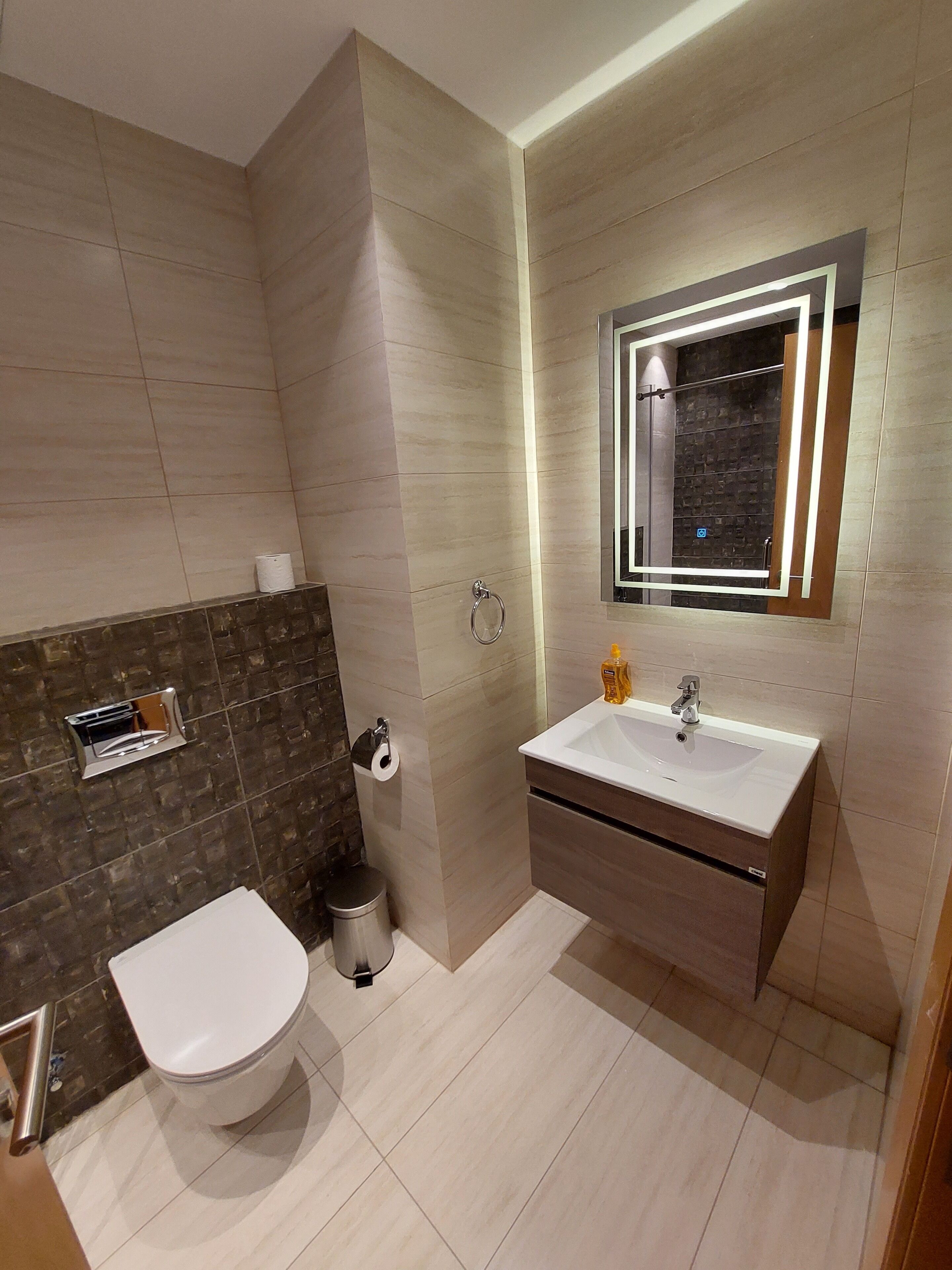 Ein modernes Badezimmer mit Toilette, Waschbecken und Spiegel.