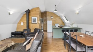 Un espace de vie chaleureux de style loft, doté d’une cheminée, d’un coin repas et d’une cuisine.