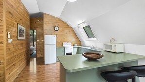 Une cuisine moderne avec des murs en bois, un îlot central vert et une petite fenêtre.
