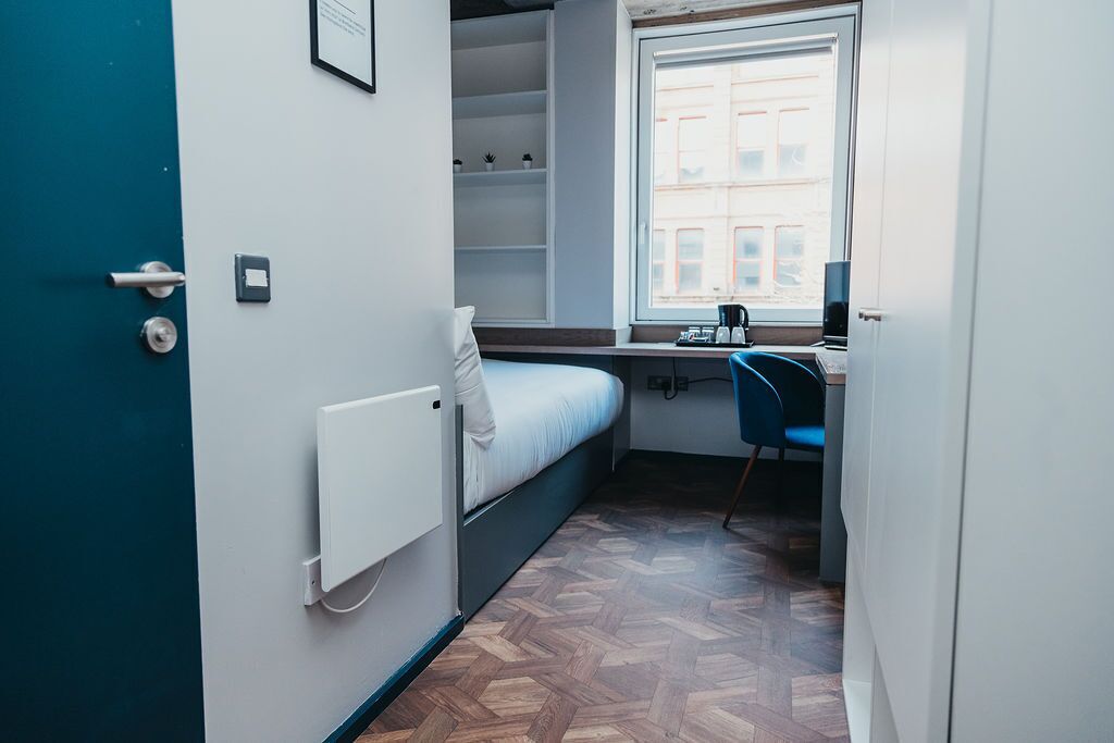A compact room with a bed, a desk, and a window.