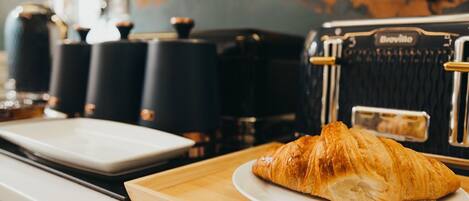 Un croissant sur une assiette, dans un coin cuisine, avec un appareil de la marque Breville en arrière-plan.