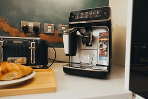 A coffee machine with a Breville brand toaster and a glass of water on a countertop.