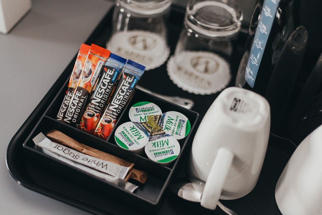 A tray with coffee pods, a white mug, and a cinnamon stick.
