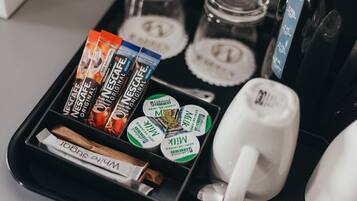 A tray with coffee pods, a white mug, and a cinnamon stick.