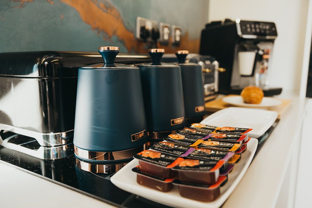 A coffee station with four coffee machines and a tray of assorted chocolates.
