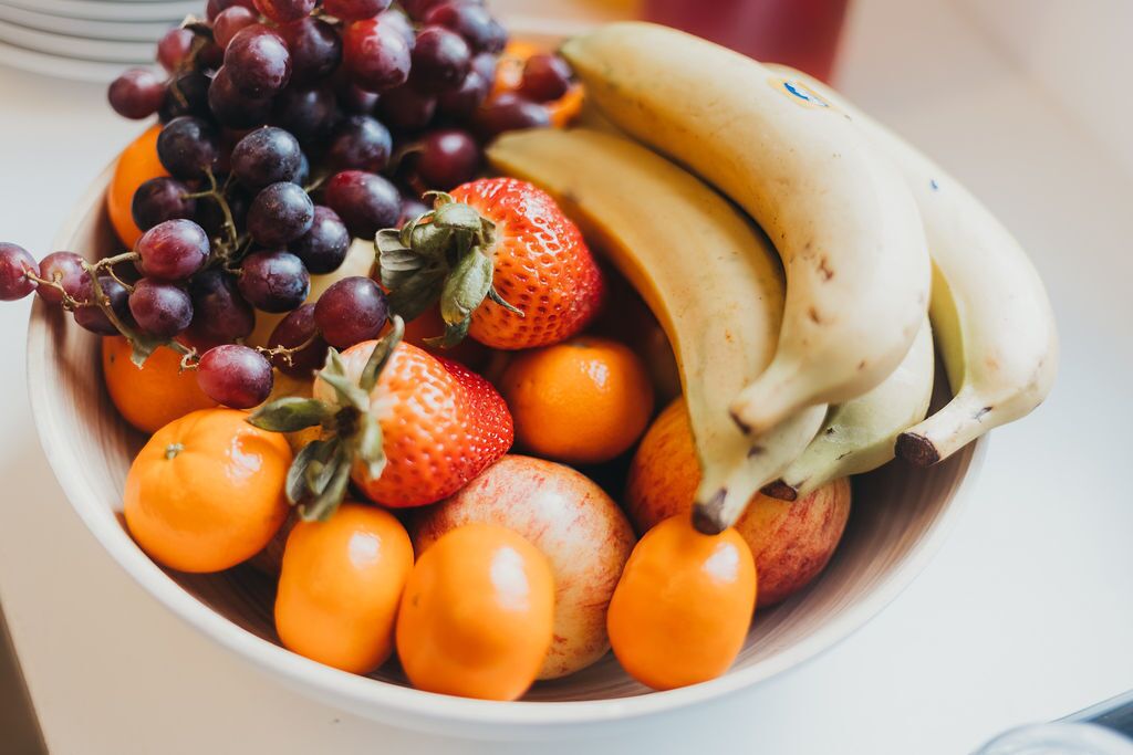 A bowl containing grapes, strawberries, bananas, and oranges.