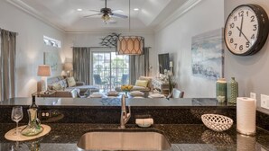A modern kitchen with a granite countertop, stainless steel sink, and a large wall clock. - Montego Bay (St. Augustine)