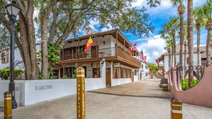 A street view with a building featuring balconies, flags, and a sign for 'St. George Street'. - Bay Bridge Beach Boho (St. Augustine)