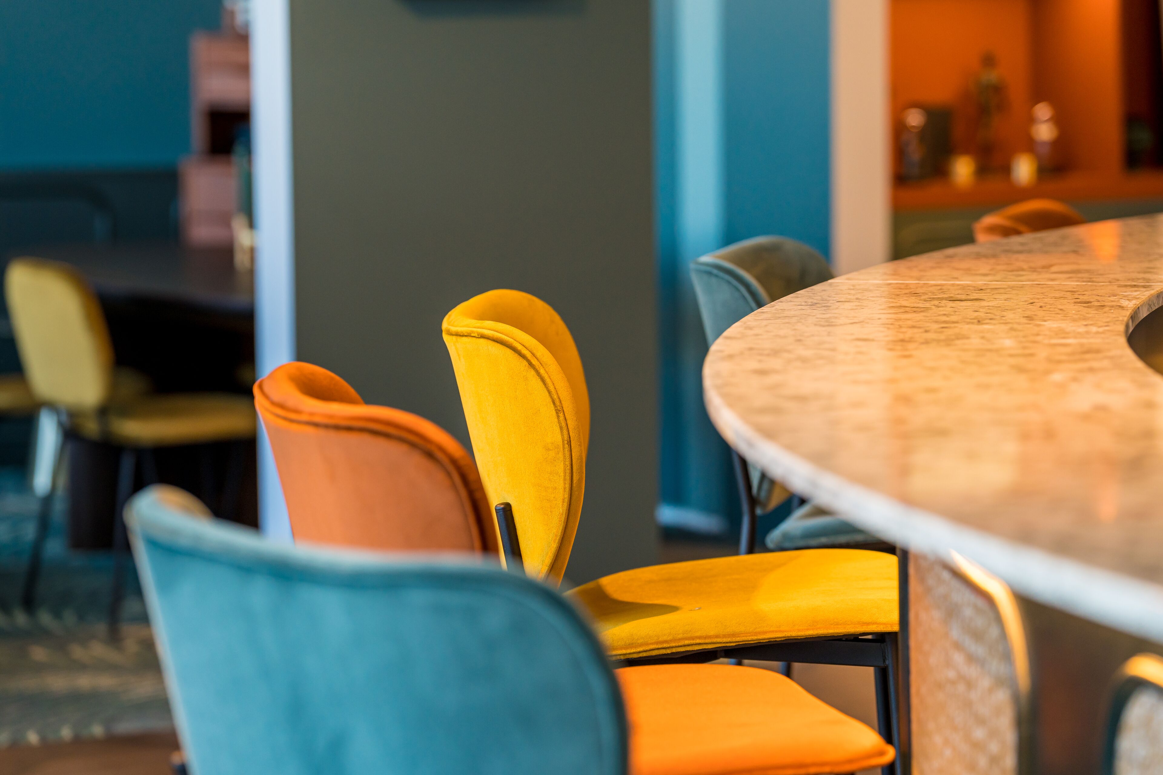A modern dining area with a round table and chairs in various colors.